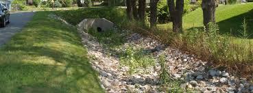 Culvert outlet in a rock-lined drainage ditch beside a path