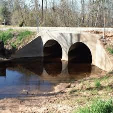 Double-arch concrete culvert carrying a stream under a road