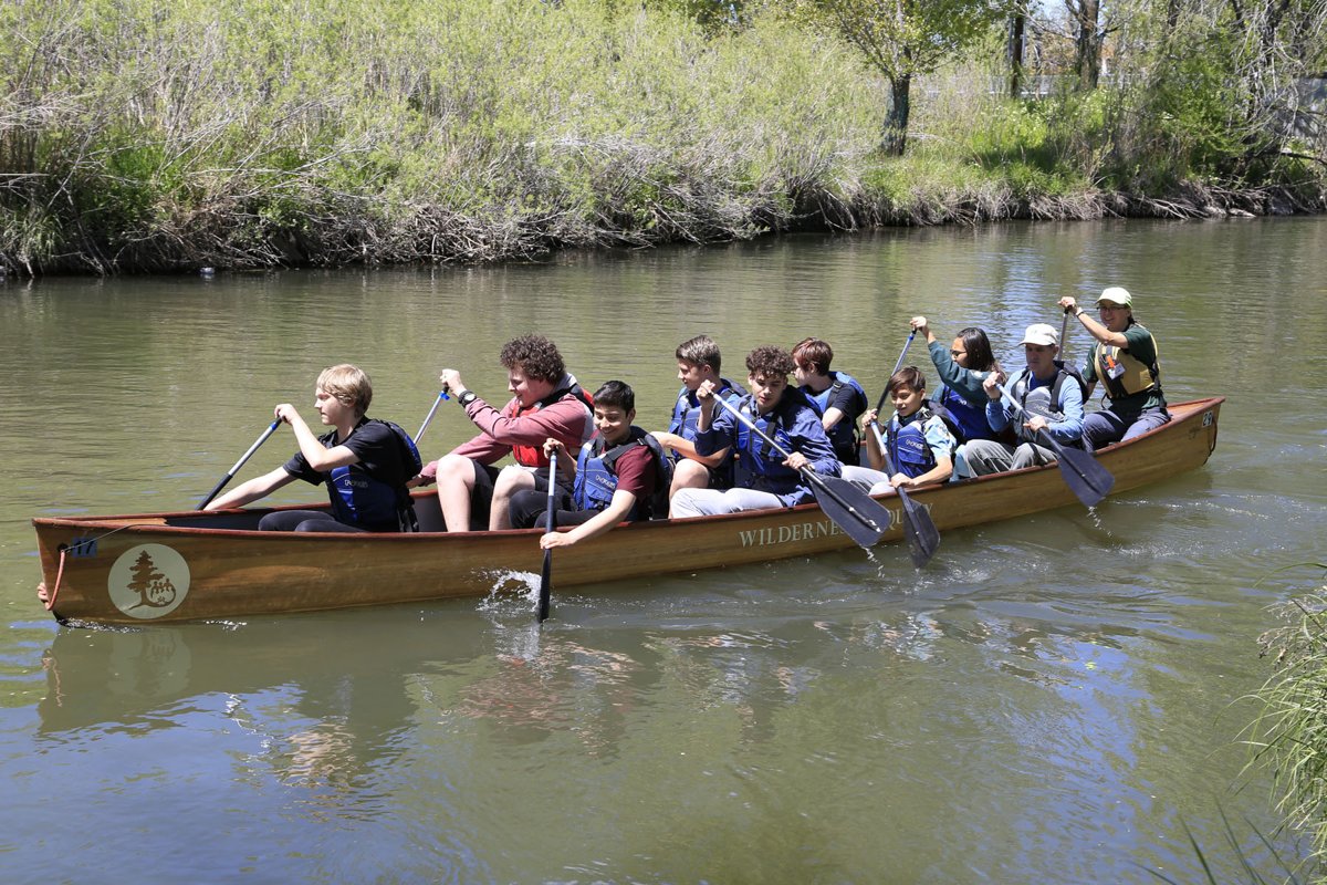 Students paddling a large canoe on the Jordan River